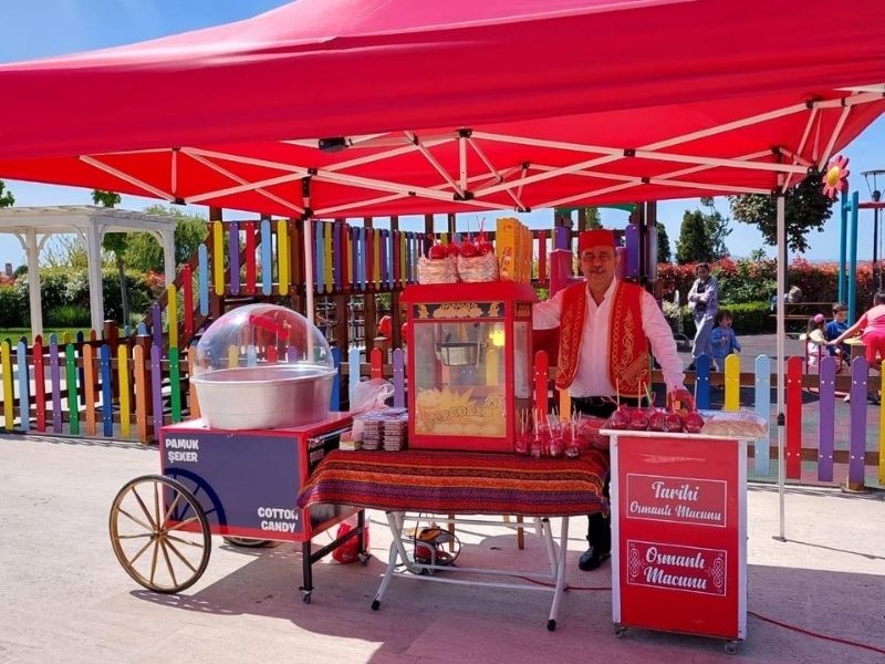 Kırmızı beyaz renkli, retro tarzda nostaljik patlamış mısır arabası etkinlik alanında servis yaparken görüntüleniyor.